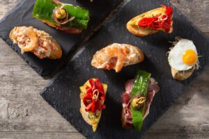 Tapas, pinchos y pintxos en la Costa Blanca: Por qué Benidorm con la calle Santo Domingo se considera un hotspot - además de lugares desde Dénia a Torrevieja. - Revista Costa Blanca - Revista Costa Blanca Tapas, pinchos y pintxos en la Costa Blanca: por qué Benidorm con la calle Santo Domingo se considera un hotspot - además de lugares desde Dénia a Torrevieja.